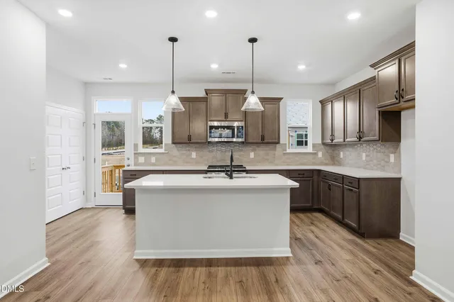 a kitchen with stainless steel appliances granite countertop a sink a stove and a wooden floors
