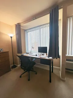 a view of a workspace with furniture and a window