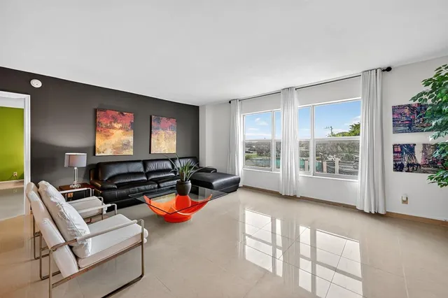 a living room with furniture a floor to ceiling window and potted plant