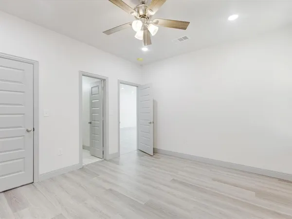 wooden floor in an empty room with a chandelier fan