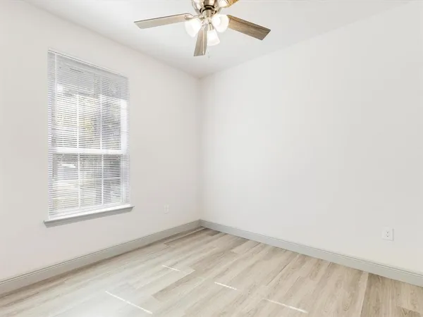 an empty room with a window and a fan