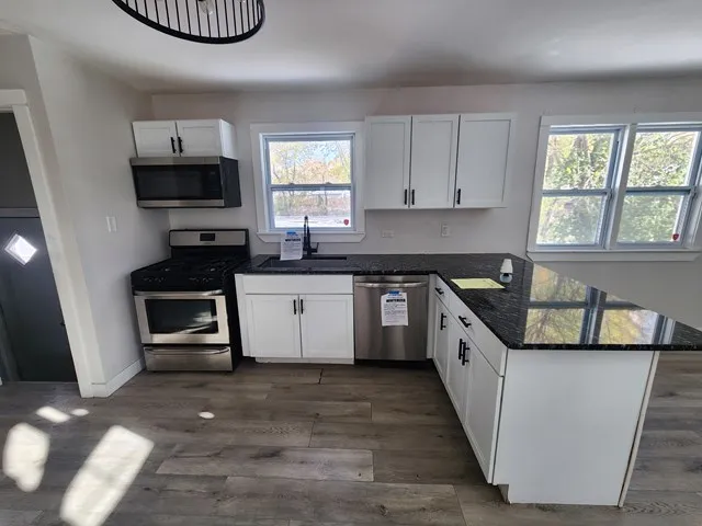 a kitchen with granite countertop a stove a sink and a microwave