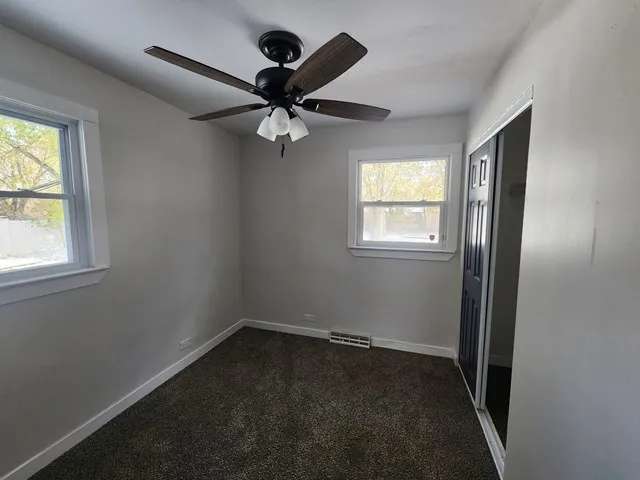 an empty room with windows and fan