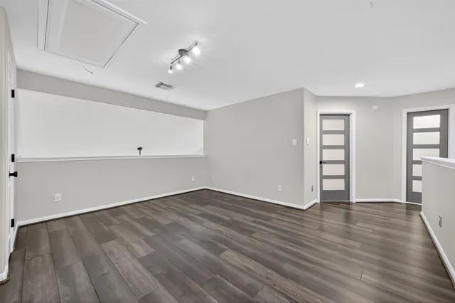 a view of an empty room with wooden floor and closet