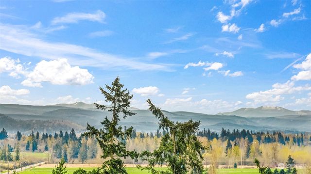 a view of grassy field with benches and trees all around