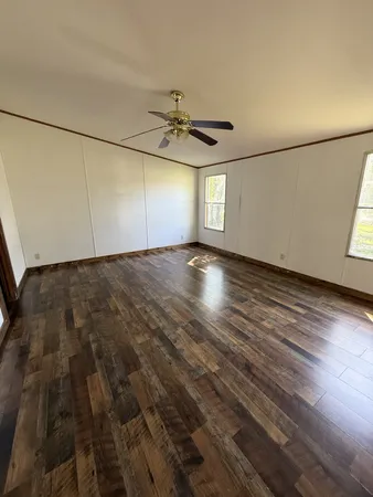 en empty room with wooden floor and windows
