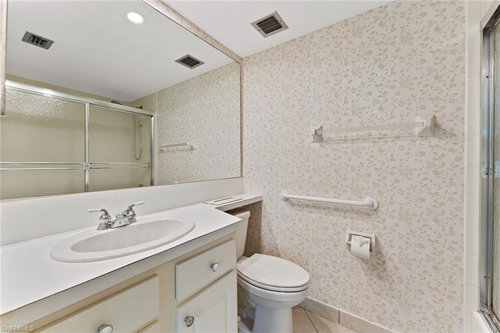 37 High Point Circle East, Unit 307 Naples, FL 34103 - Photo 16 of 20 a bathroom with a granite countertop sink a toilet and a mirror