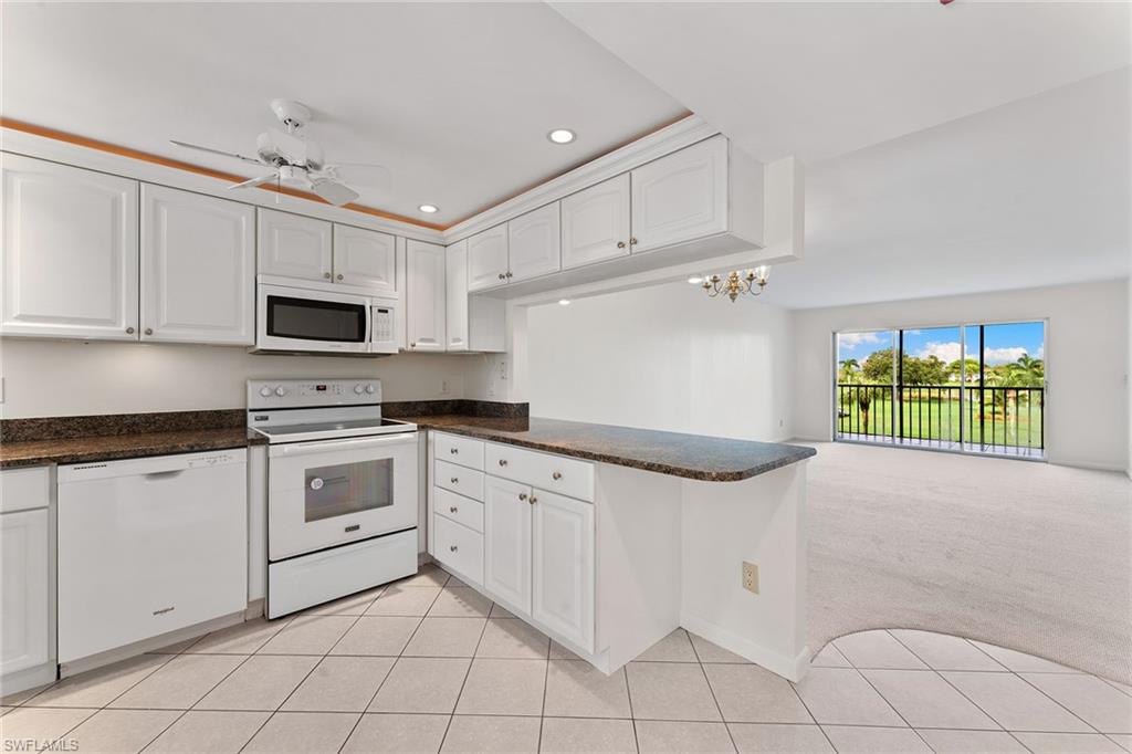 37 High Point Circle East, Unit 307 Naples, FL 34103 - Photo 8 of 20 a kitchen with granite countertop white cabinets and white appliances