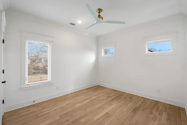 a view of empty room with wooden floor and fan
