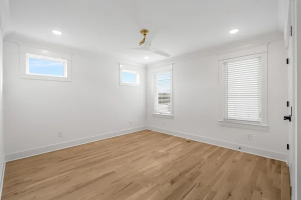 an empty room with wooden floor cabinet and windows