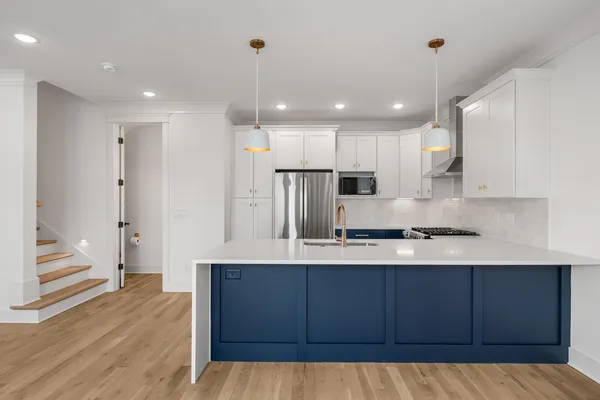 a kitchen with stainless steel appliances granite countertop a sink a stove a refrigerator and a oven with wooden floor