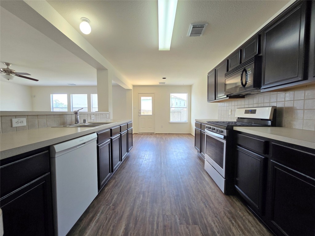 22911 Twisting Maple Court Spring, TX 77373 - Photo 22 of 37 a kitchen with stainless steel appliances wooden floors wooden cabinets and sink