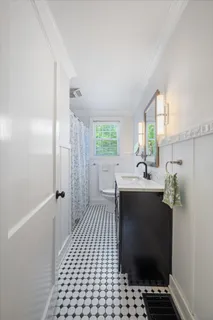 a bathroom with a sink a toilet a window and shower