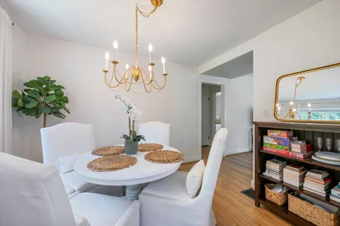 a view of a dining room with furniture a chandelier and wooden floor