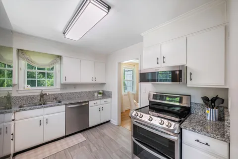 a kitchen with stainless steel appliances granite countertop a sink stove and cabinets