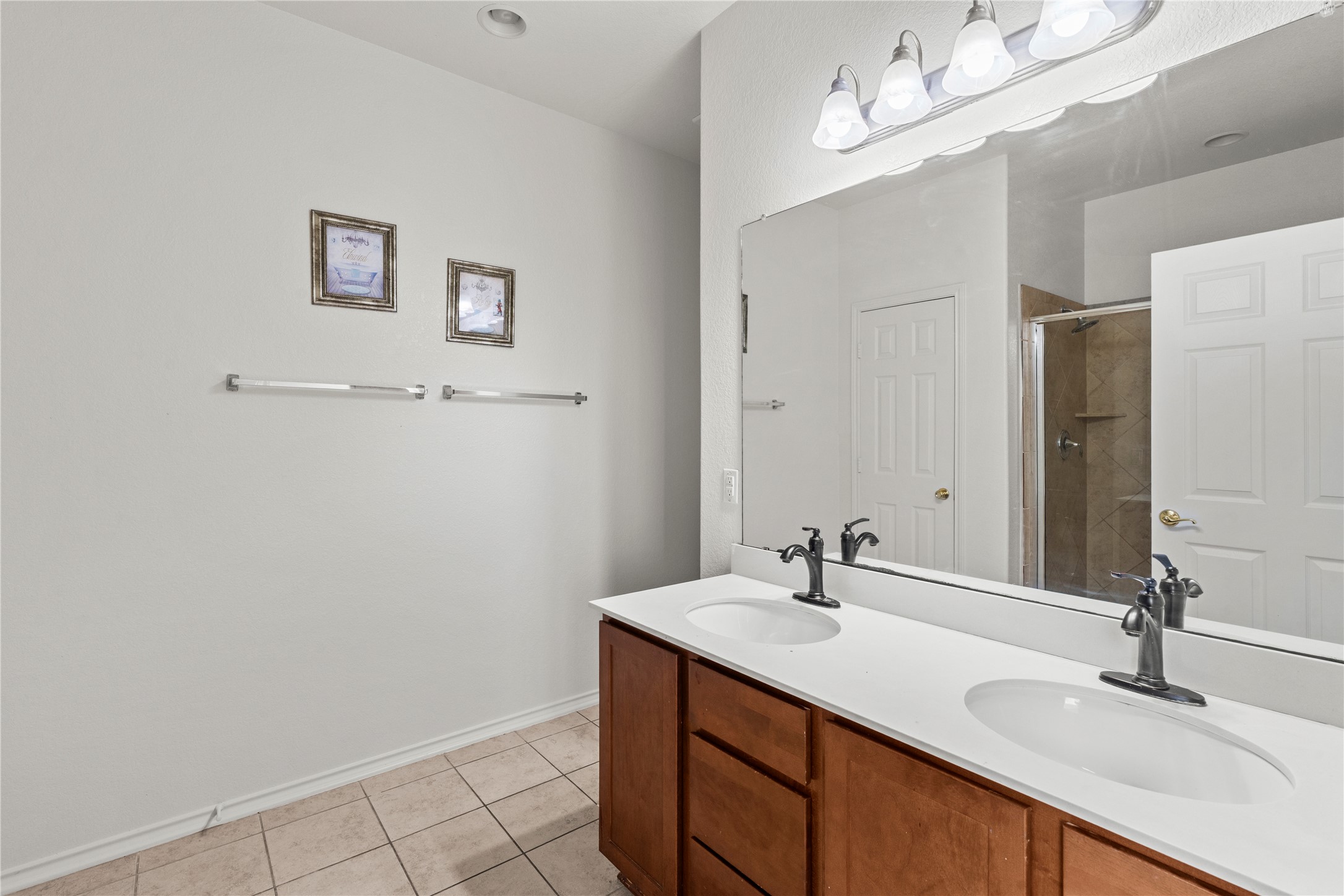 8613 Capitol View Drive Austin, TX 78747 - Photo 13 of 33 Double vanity with sleek white countertops and warm wood cabinetry, enhancing a functional bathroom space.