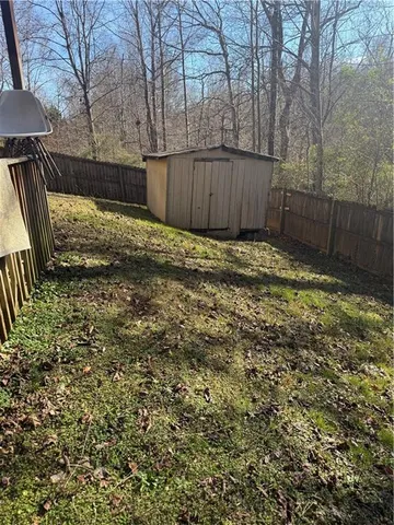 a view of a backyard with large trees and wooden fence