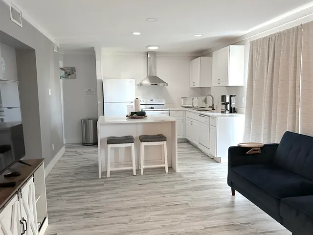 a kitchen with stainless steel appliances granite countertop a table chairs stove a sink dishwasher and cabinets with wooden floor