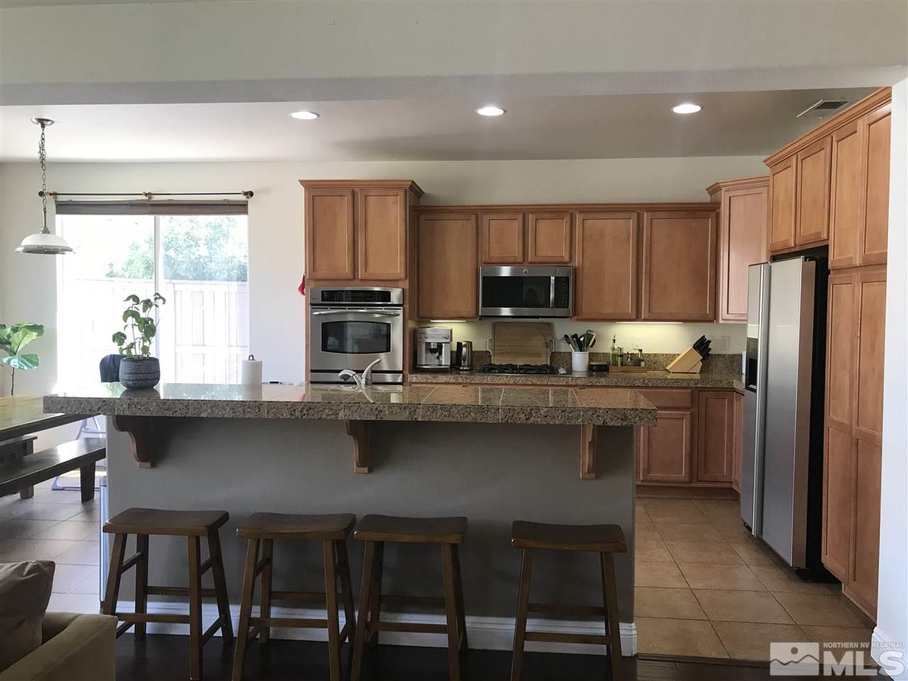 615 Equine Court Reno, NV 89521 - Photo 4 of 25 a kitchen with kitchen island granite countertop a table chairs microwave and refrigerator