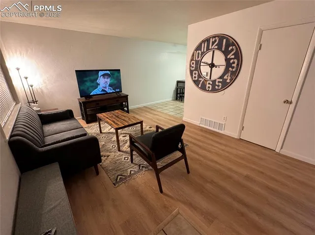 a living room with furniture a flat screen tv and a wall clock