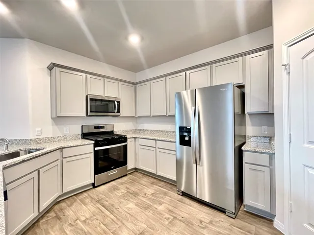 a kitchen with stainless steel appliances granite countertop a refrigerator stove and sink