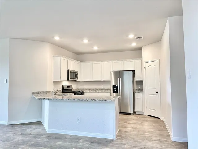 a kitchen with stainless steel appliances granite countertop a refrigerator and a stove