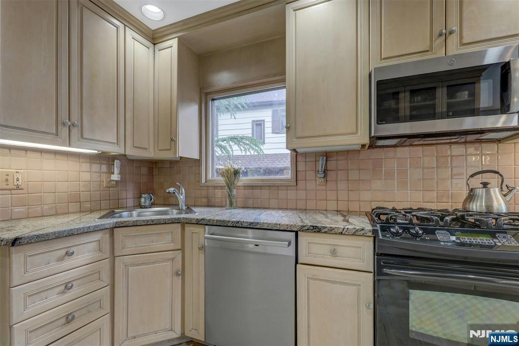 548 Standish Road Teaneck, NJ 07666 - Photo 15 of 28 a kitchen with stainless steel appliances granite countertop white cabinets and a stove top oven