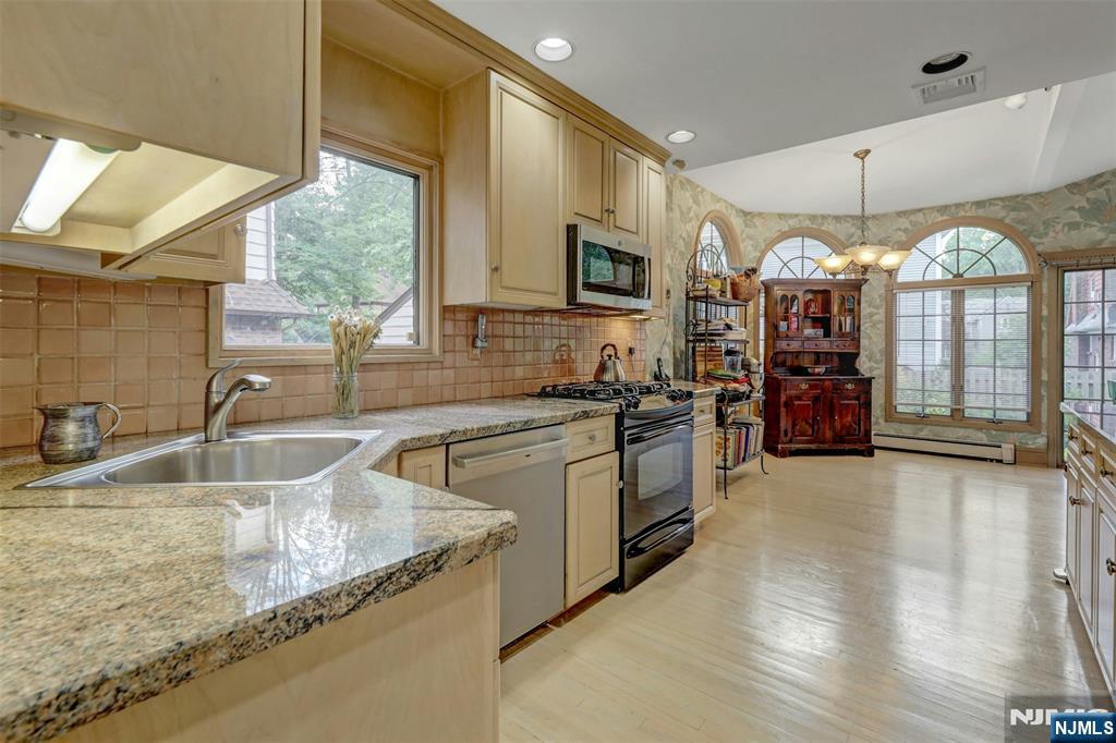 548 Standish Road Teaneck, NJ 07666 - Photo 16 of 28 a kitchen with stainless steel appliances granite countertop a sink a stove and a wooden floors