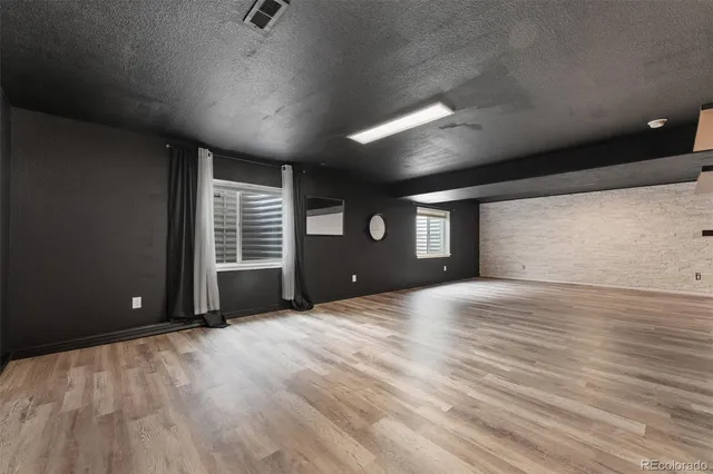 a view of an empty room with window and wooden floor