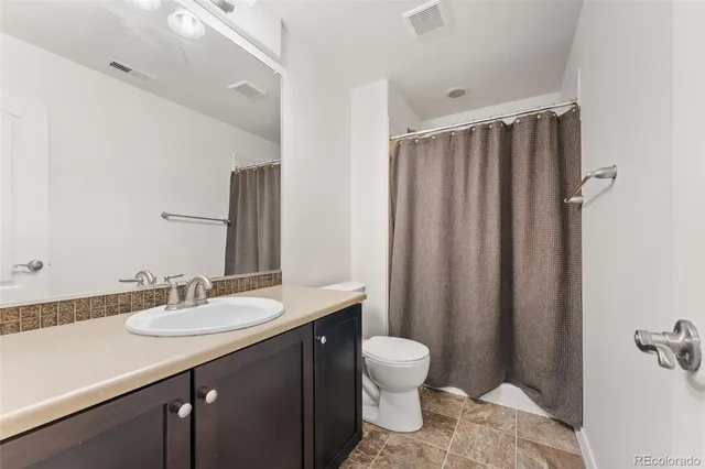 a bathroom with a sink a toilet a mirror and shower curtain