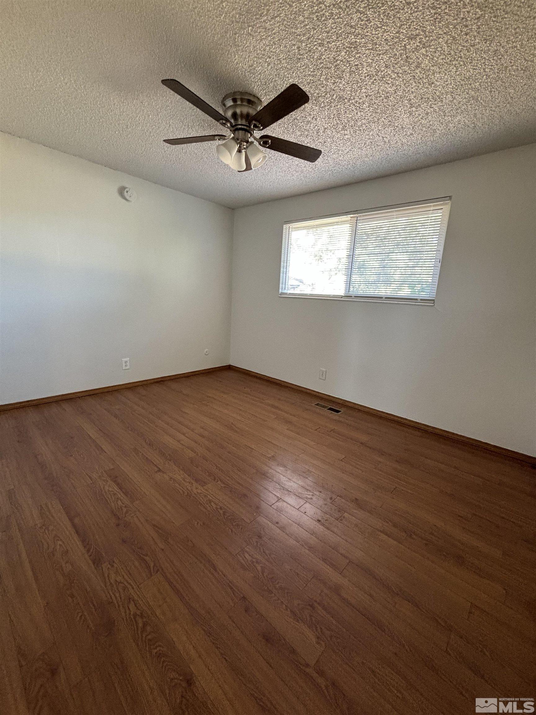 9405 Fremont Way Reno, NV 89506 - Photo 4 of 14 an empty room with wooden floor ceiling fan and windows
