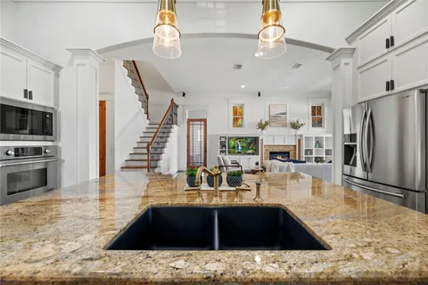 a kitchen with kitchen island granite countertop a refrigerator a stove and white cabinets with wooden floor