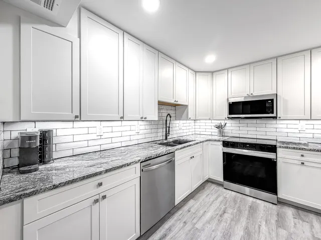 a kitchen with stainless steel appliances granite countertop a sink a stove a microwave and cabinets