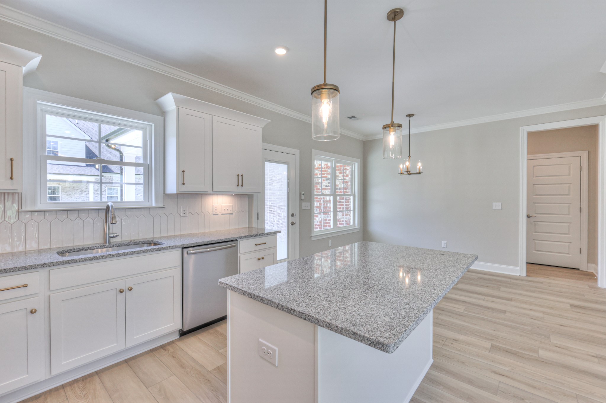 437 Ruby Oaks Lane Murfreesboro, TN 37128 - Photo 10 of 38 a kitchen with center island a sink dishwasher a dining table and chairs with wooden floor