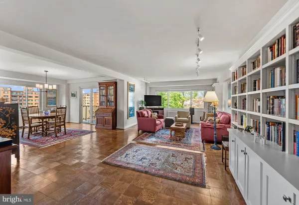 a living room with furniture lots of books and a large window