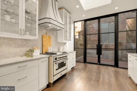 a kitchen with stainless steel appliances granite countertop a stove a sink and a refrigerator with wooden floor