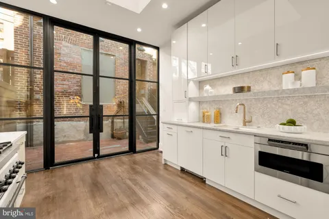 a kitchen with stainless steel appliances granite countertop a stove a sink and a refrigerator with wooden floor