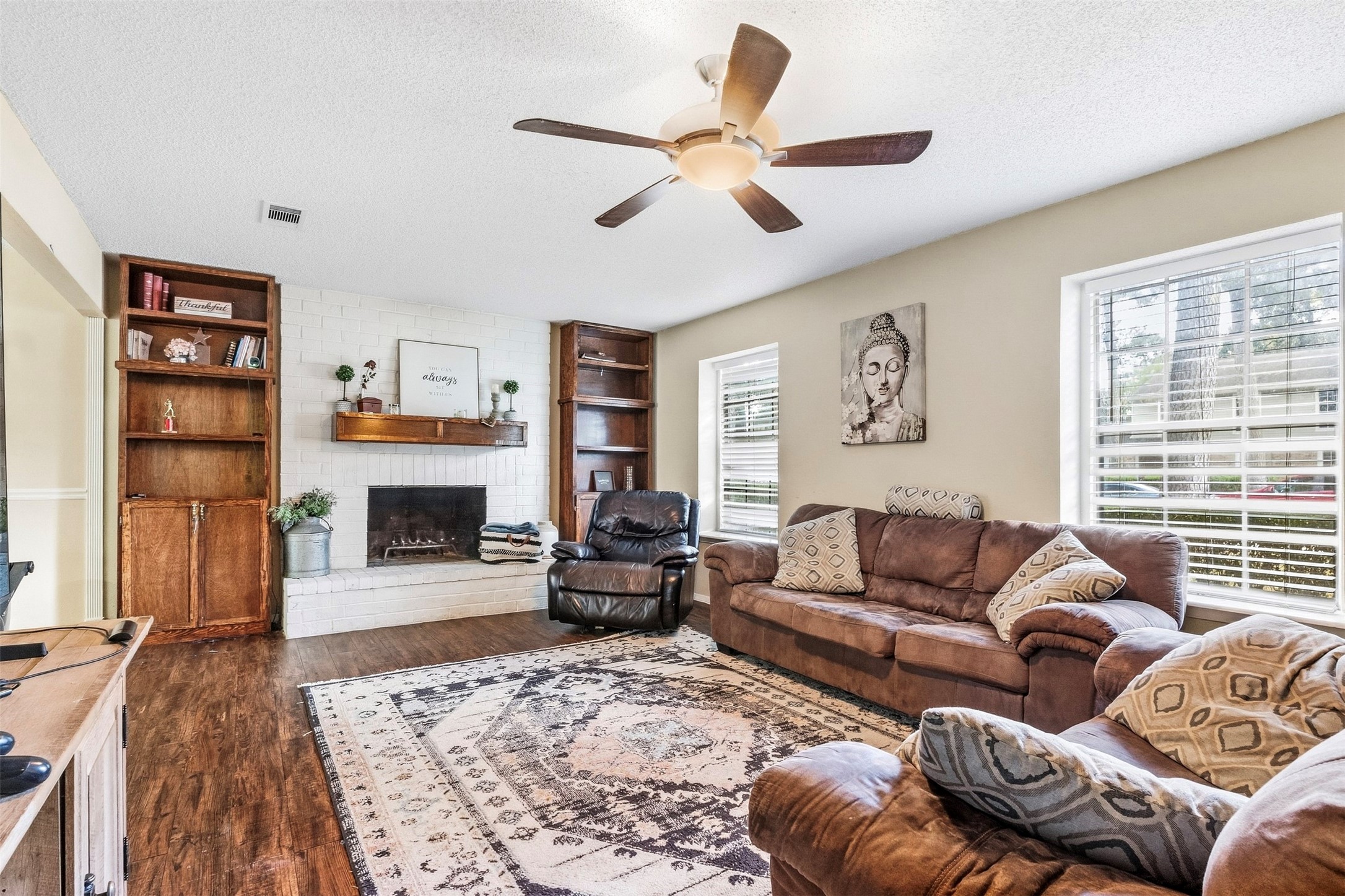 25539 Chapel Ridge Lane Spring, TX 77373 - Photo 3 of 40 Plenty of space for hosting! The inviting living room features wood-look flooring, a brick fireplace with decorative shelving, and large windows that bring in plenty of natural light.