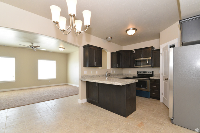 241 West Ridge Road Saratoga Springs, UT 84045 - Photo 5 of 21 Kitchen featuring dark wood cabinetry, light-toned countertops, stainless steel appliances, and tile flooring