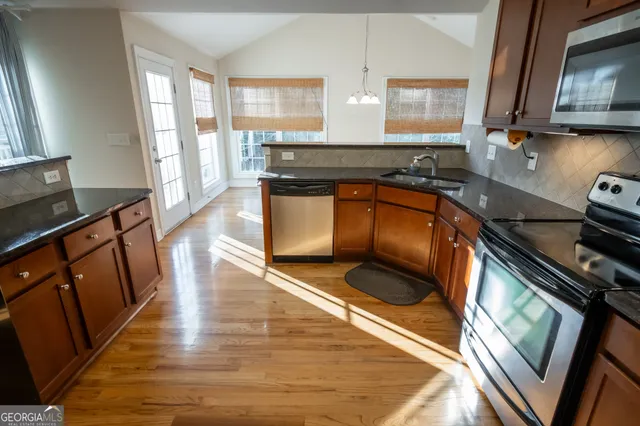 a kitchen with stainless steel appliances granite countertop wooden cabinets a stove top oven a sink and dishwasher