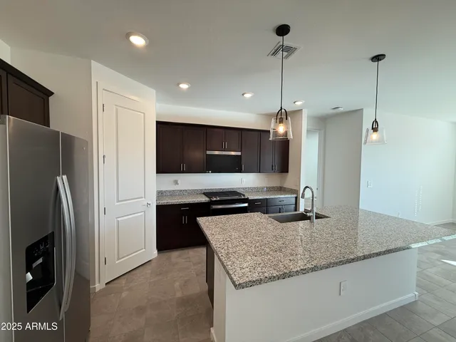 a kitchen with stainless steel appliances granite countertop a sink a refrigerator and a stove