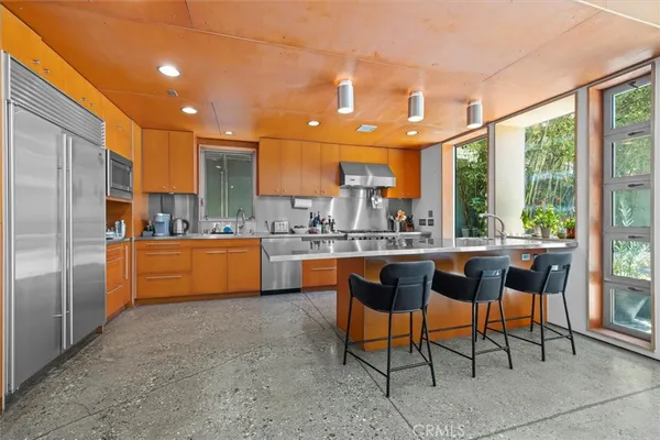 a kitchen with kitchen island a large window in it and stainless steel appliances