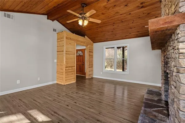 a view of an empty room with wooden floor fireplace and a window