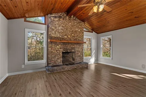 an empty room with wooden floor chandelier and windows