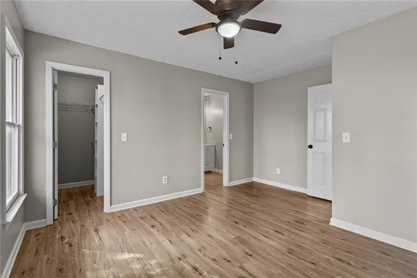 a view of empty room with wooden floor and fan