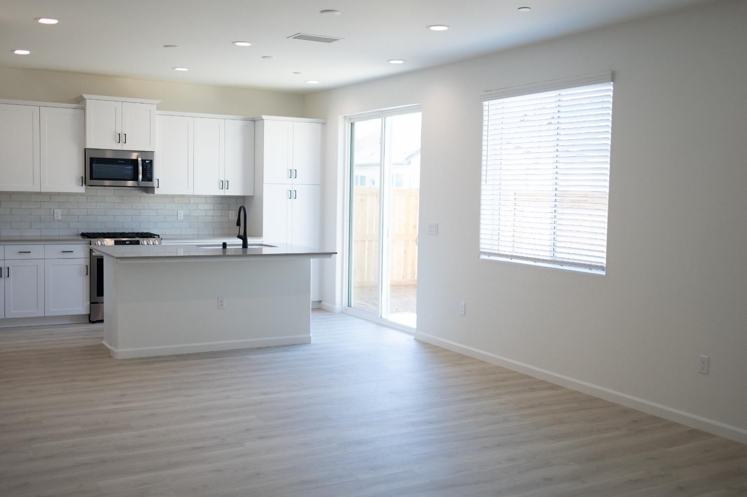 696 Grace Way Madera, CA 93636 - Photo 3 of 19 a large kitchen with stainless steel appliances granite countertop a stove a sink and white cabinets with wooden floor
