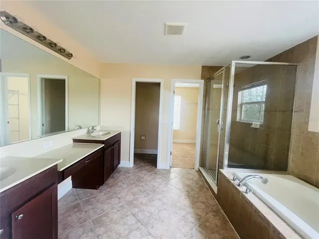 a spacious bathroom with a tub sink shower and mirror