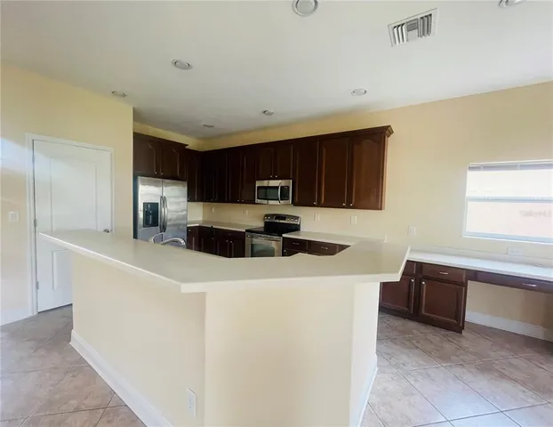 a kitchen with stainless steel appliances a refrigerator a sink a stove a microwave and wooden cabinets