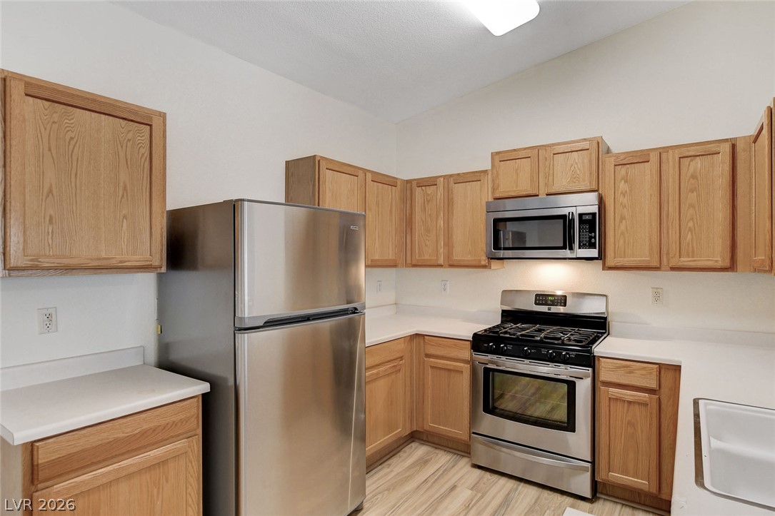2052 Quarry Ridge Street, Unit 201 Las Vegas, NV 89117 - Photo 9 of 25 Bright, modern kitchen with warm wood cabinetry and a suite of stainless steel appliances.