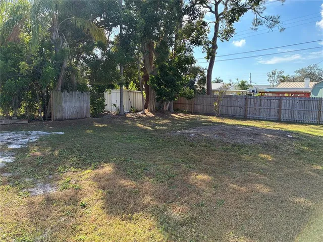 a view of a backyard with large trees and wooden fence